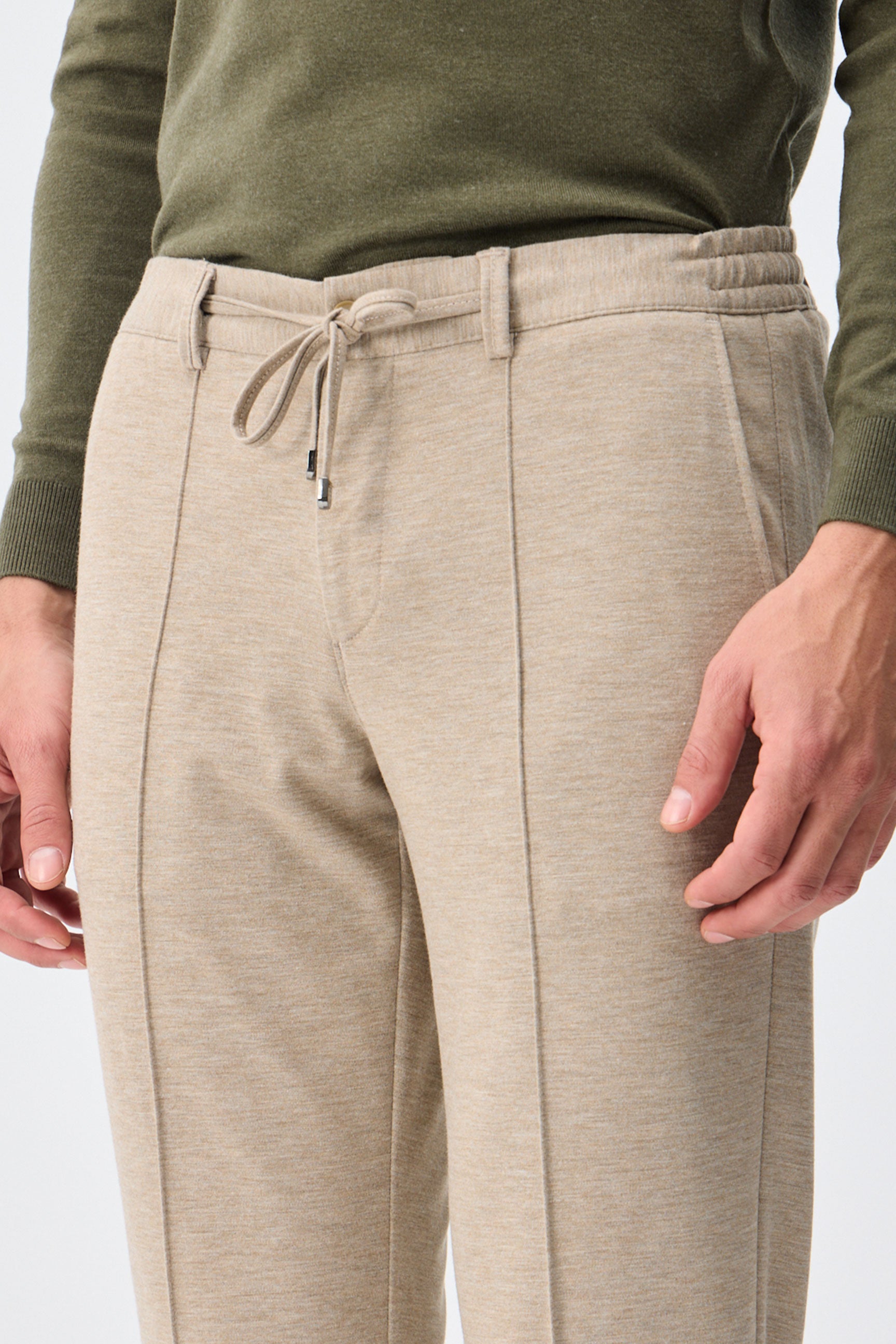 Herenbroek met trekkoord in taupe- of havermoutbeige kleur, getailleerde pasvorm en taps toelopende pasvorm.