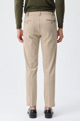 Herenbroek met trekkoord in taupe- of havermoutbeige kleur, getailleerde pasvorm en taps toelopende pasvorm.