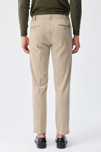 Herenbroek met trekkoord in taupe- of havermoutbeige kleur, getailleerde pasvorm en taps toelopende pasvorm.