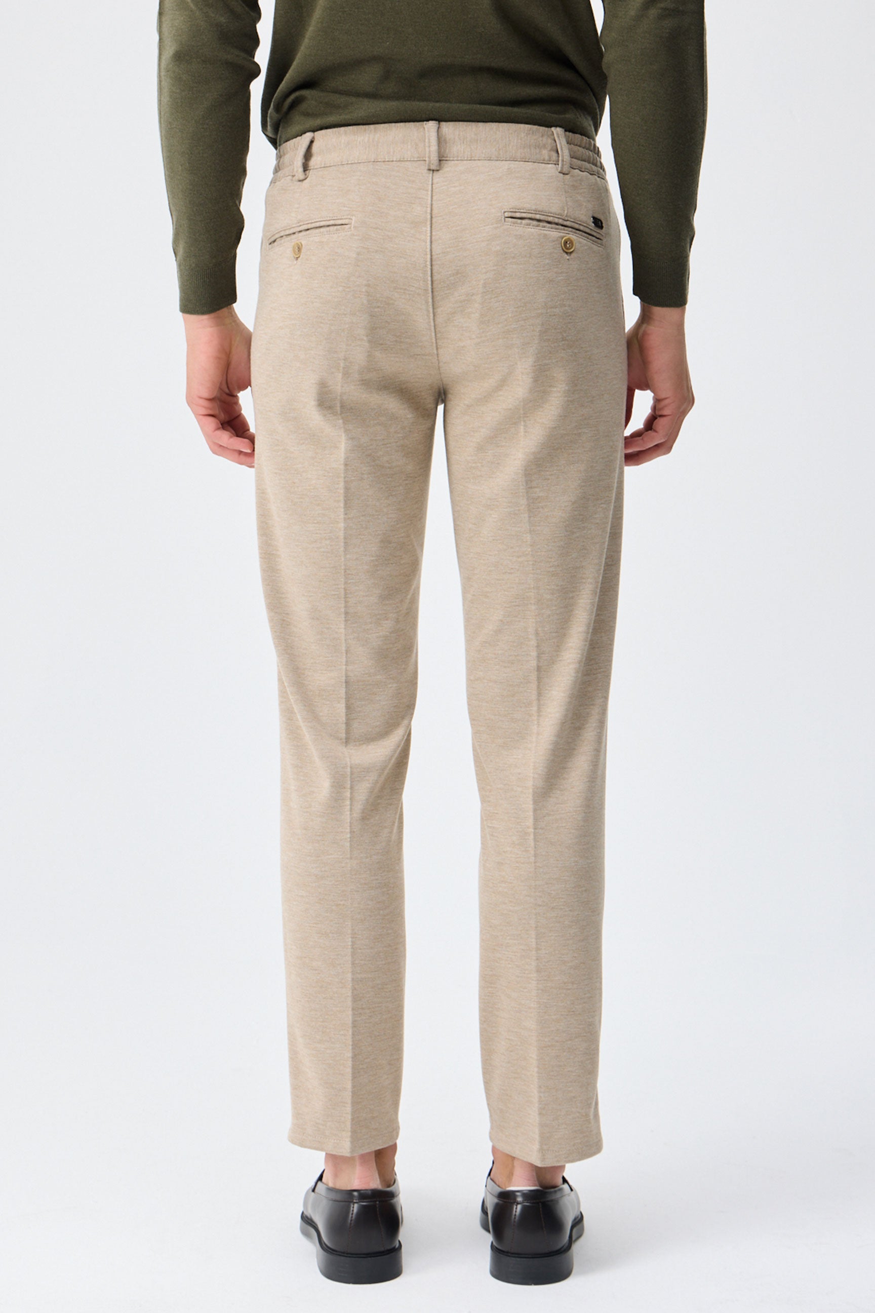 Herenbroek met trekkoord in taupe- of havermoutbeige kleur, getailleerde pasvorm en taps toelopende pasvorm.