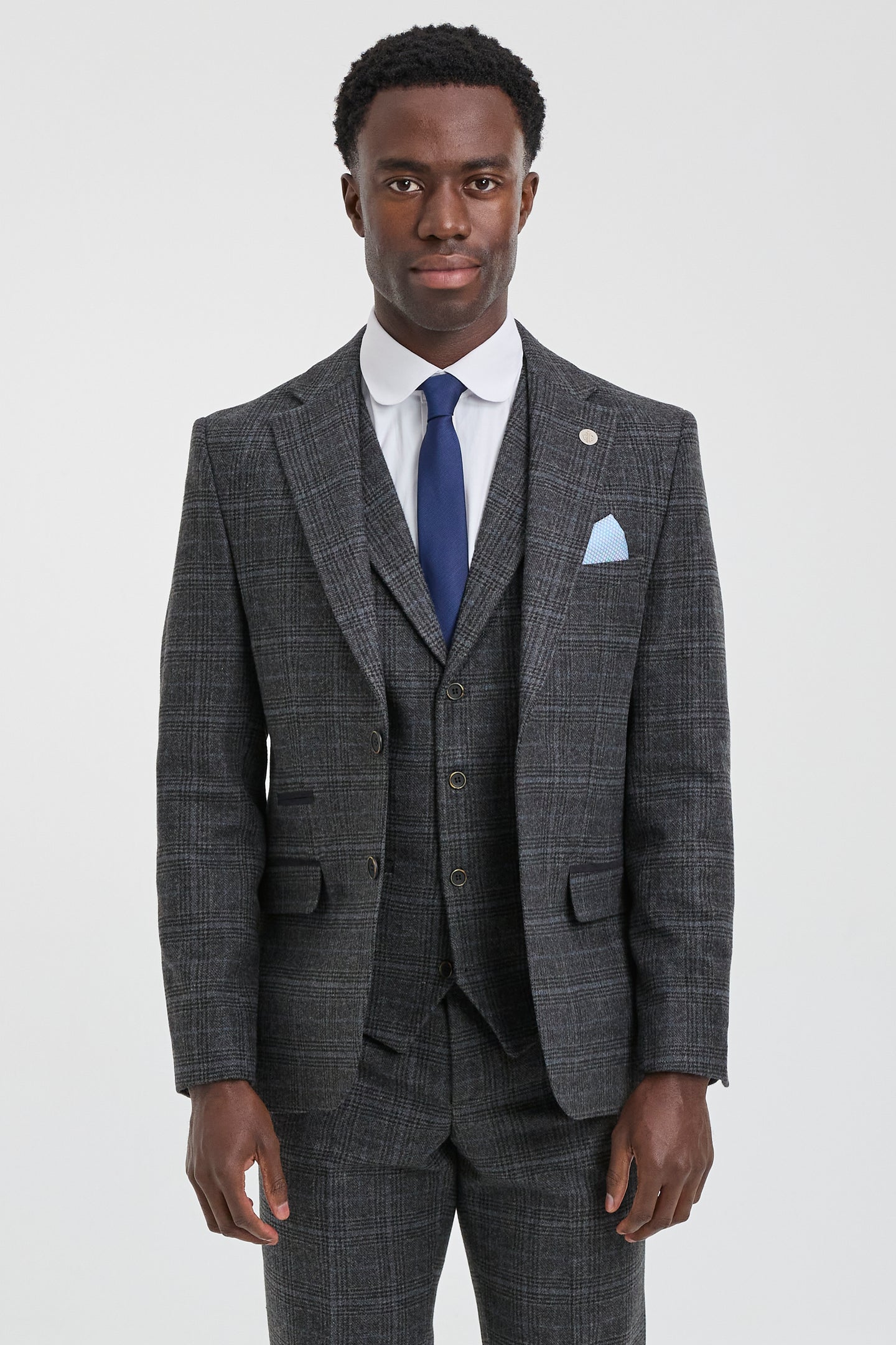 Man wearing a gray checkered suit with a blue tie and pocket square on a white background